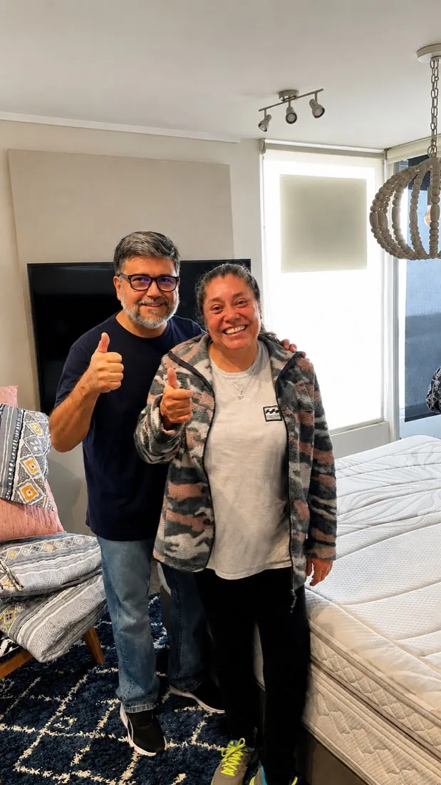 Pareja de clientes sonriendo y con el pulgar arriba junto a su cama recién instalada por Yoru Express