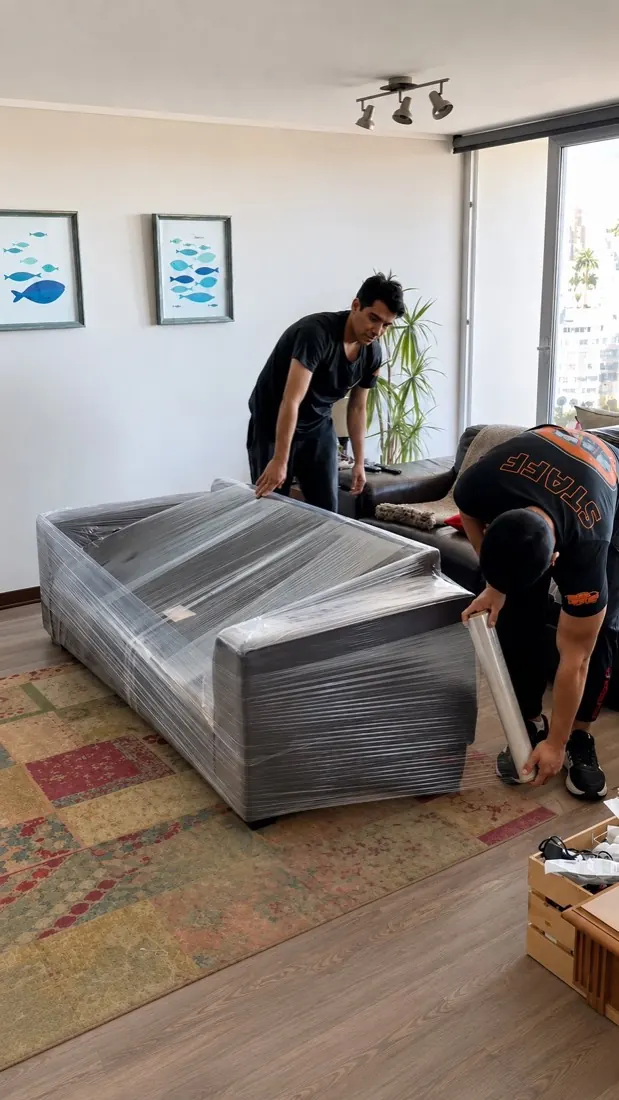 Trabajador de Yoru Express embalando un sofá con plástico film antes de una mudanza
