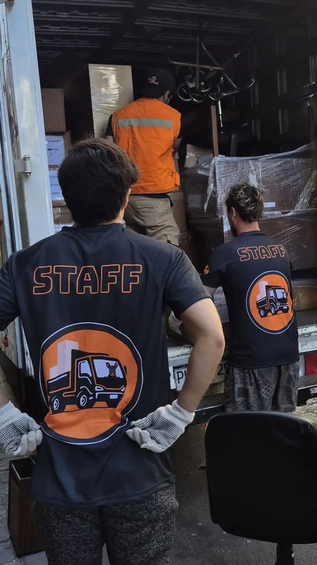Trabajadores de Yoru Express con poleras STAFF cargando muebles en un camión