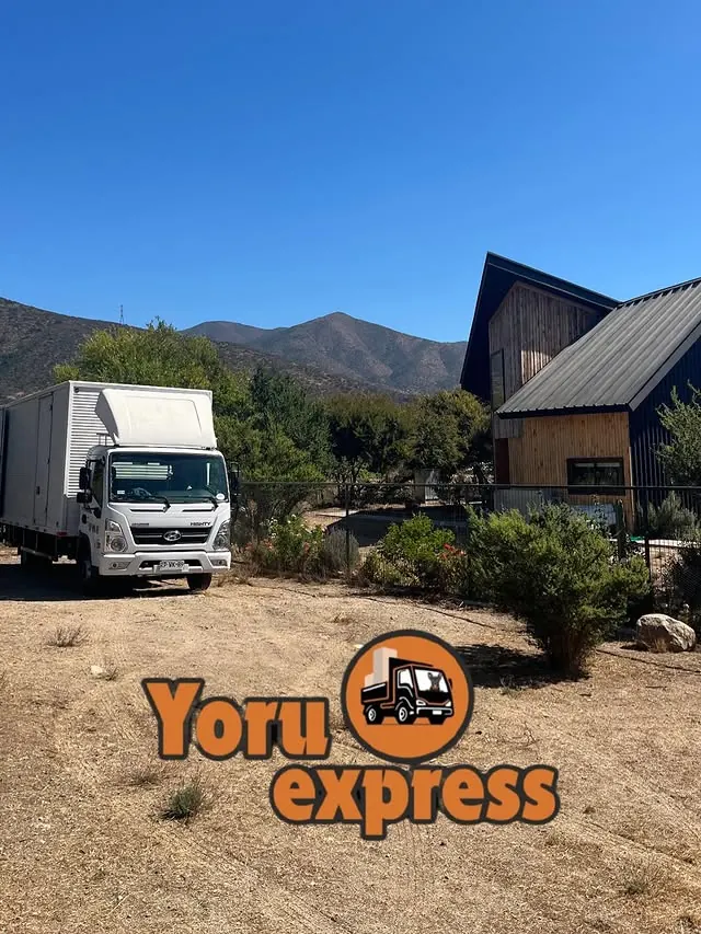 Camión de Yoru Express estacionado frente a una cabaña con vista a la cordillera