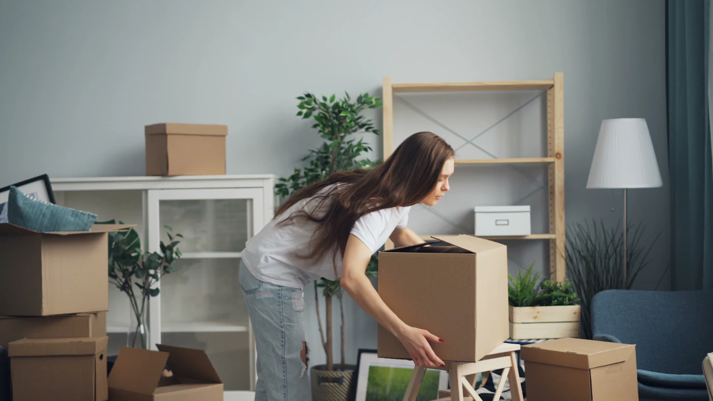 Mujer embalando cajas en su living antes de una mudanza